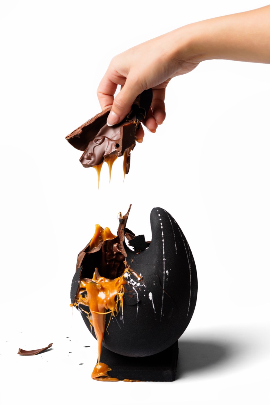 A handmade Eclectic Collection chocolate shell cracked open over salted caramel