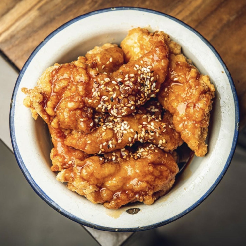 Korean fried chicken glazed in sauce, in a bowl ready to travel